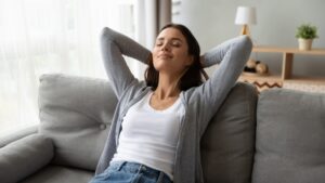 woman-leaning-back-on-couch-with-eyes-closed-looking-content